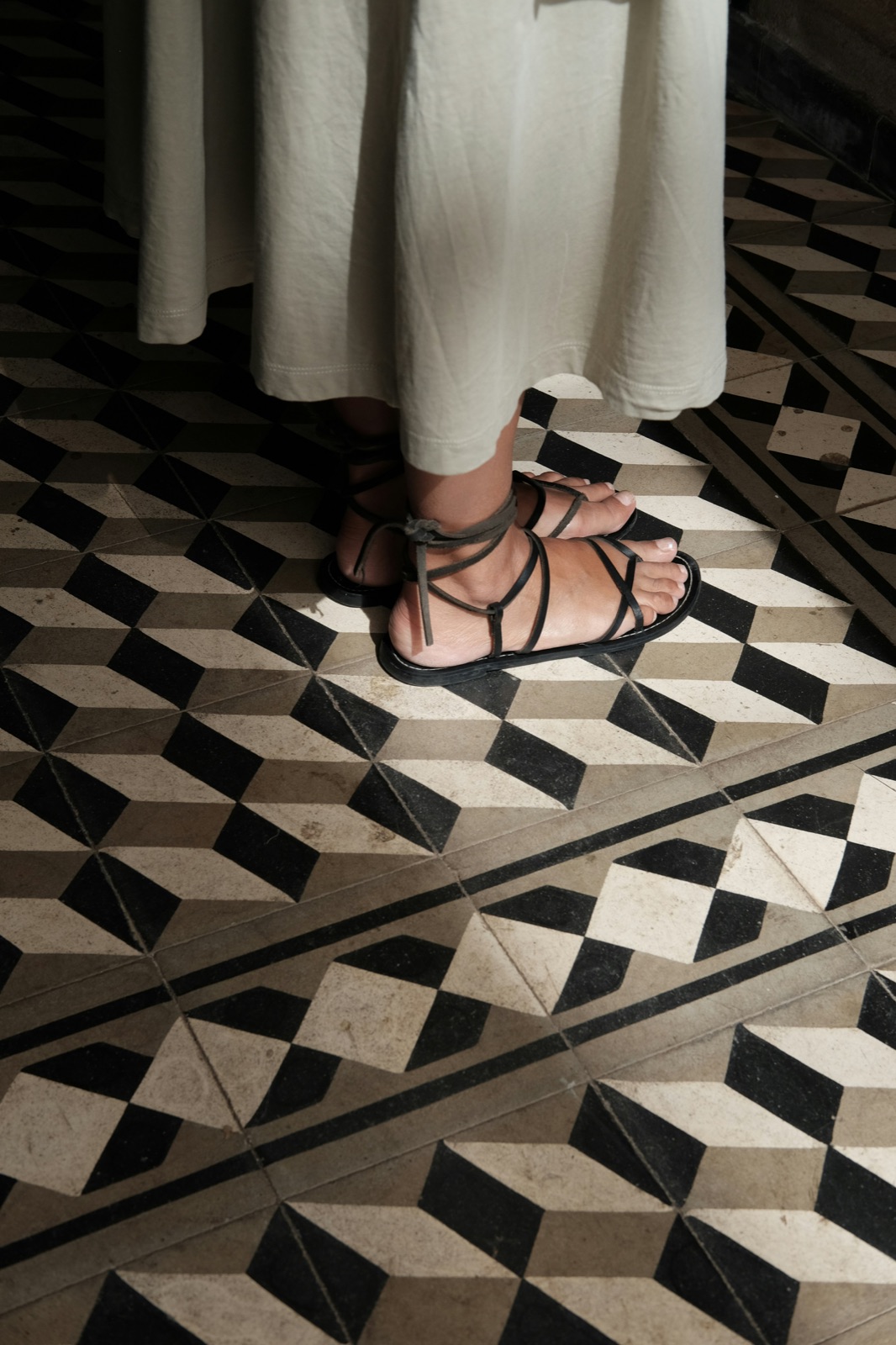 Verzorgde voeten in sandalen op een grafische tegelvloer